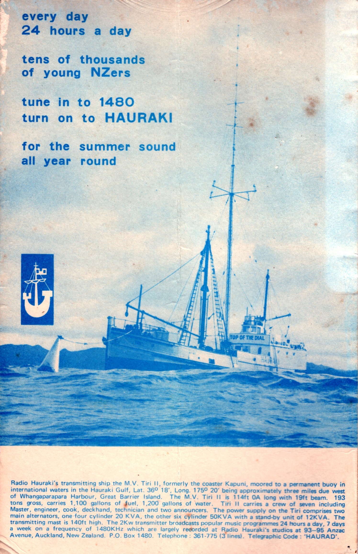 Image is a postcard of a blue and white photograph of a coaster type boat with a tall central mast set up for AM radio transmission. The boat is anchored to a small buoy. On top of the image, the words 'every day 24 hours a day tens of thousands of young NZers tune in to 1480 tune on to HAURAKI for the summer sound all year round' are written in blue. Below the image is written in very small writing: Radio Hauraki's transmitting ship the M.V. Tiri II, formerly the coaster Kapuni, moored to a permanent buoy in international waters in the Hauraki Gulf, Lat. 36° 18', Long. 175° 20' being approximately three miles due west of Whangaparapara Harbour, Great Barrier Island. The M.V. Tiri II is a 124ft 0A long in 19ft beam. 193 tons gross, carries 1,100 gallons of fuel, 1,200 gallons of water. Tiri II carries a crew of seven including Master, engineer, cook, deckhand, technician and two announcers. The power supply on the Tiwi comprises two main alternators, one four cylinder 20 KVA, the other side cylinder 50 KVA with a stand-by unit of 12 KVA. The transmitting mast is 140ft high. The 2Kw transmitter broadcasts popular music programmes 24 hours a day, 7 days a week on a frequency of 1480KHz which are largely recorded at Radio Hauraki's studios at 93-95 Anzac Avenue, Auckland, New Zealand. P.O. Box 1480. Telephone: 361-775 (3 lines). Telegraphic Code: 'HAURAD'.
